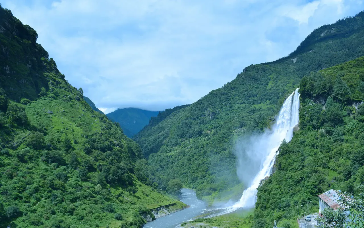 Nuranang Waterfall flowing into a green mountain valley