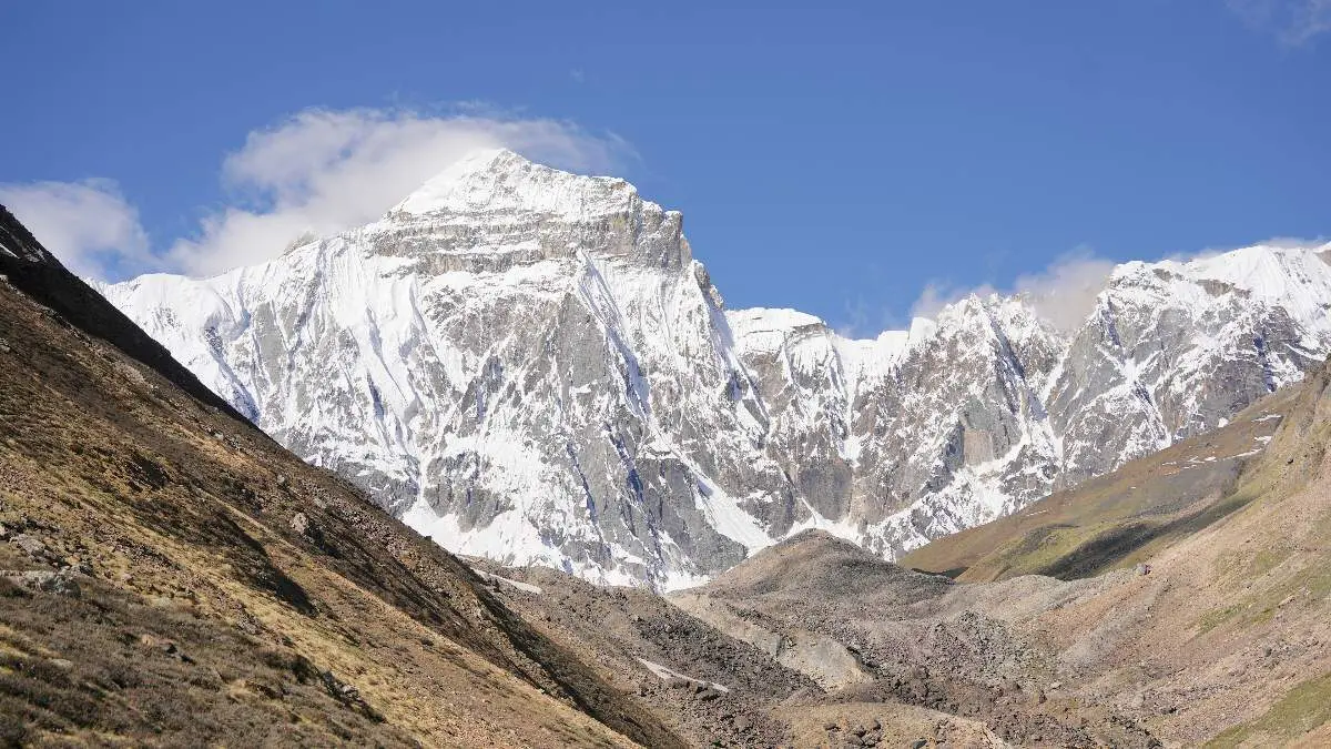 A snow-covered mountain rising above a rocky high-altitude valley